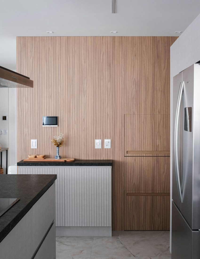 Conception d'une cuisine sur mesure avec mur d'accent en tasseaux de bois et plan de travail en pierre sombre, réalisée par l'architecte d'intérieur MyWay.