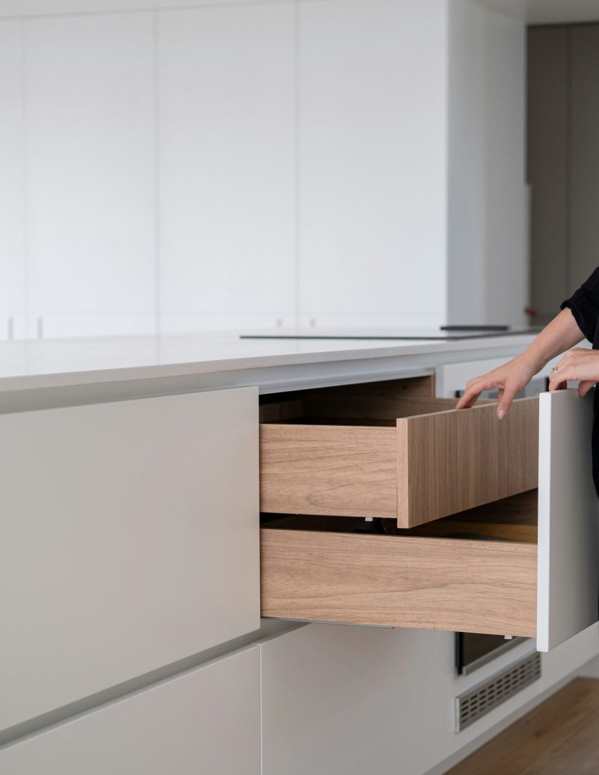 Myway: Détail de finitions sur mesure : tiroirs de cuisine en bois intégrés dans un îlot blanc minimaliste.